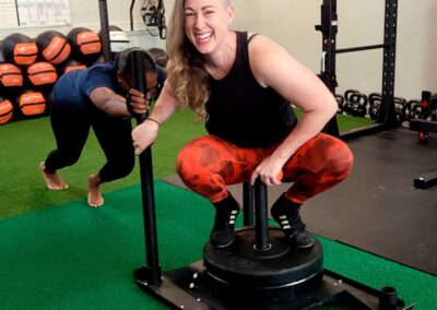 Coach Kat sitting on sled push as a client pushes it